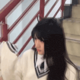 a girl with long black hair is standing next to a railing .