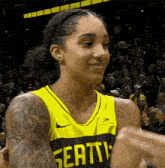 a female basketball player wearing a yellow and green jersey is giving a high five to another player .