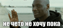 a man in a black hoodie is smiling and waving his hand in a meme .