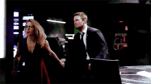 a man and woman are holding hands in a dark room