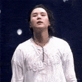 a man with long hair is wearing a white shirt with the word agustd on it .