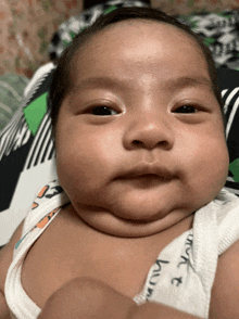 a baby is wearing a white tank top that says work on it