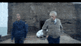 two men are walking in front of a concrete wall with a sign that says ' a ' on it