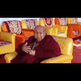 a man in a purple robe is sitting in a chair holding a microphone