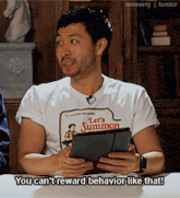 a man wearing a let 's summon t-shirt holds a tablet