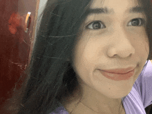 a close up of a woman 's face with a purple shirt