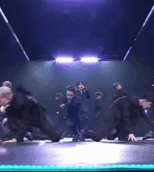 a group of dancers are performing on a stage with purple lights