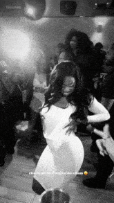 a woman in a white dress is dancing in front of a crowd with the words source above her