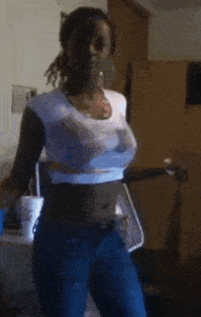 a woman in a white shirt and blue jeans is dancing in a room