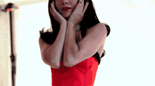 a woman in a red dress is holding her hands to her face
