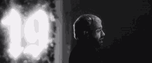 a black and white photo of a man standing in front of a light with the number 19 behind him .