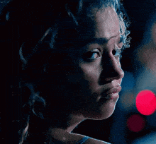 a close up of a woman 's face with smoke coming out of her hair in a dark room .