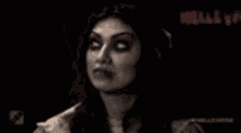 a woman with blood on her face is standing in a dark room .