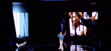 a man singing on a stage in front of a screen that says " eu de no "