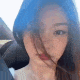 a close up of a woman 's face with her hair blowing in the wind while sitting in a car .