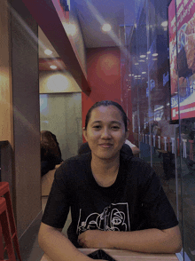 a woman sits at a table in front of a sign that says chicken nuggets