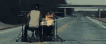 a man playing drums in the middle of a road
