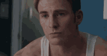 a close up of a man 's face with a white tank top
