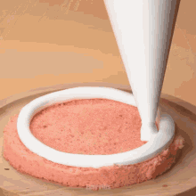 a cake is being frosted with white frosting on a wooden plate