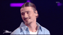 a man is smiling in front of a screen that says star academy on it