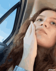 a woman in a car with her hand on her face