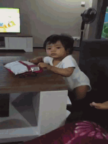 a baby is sitting at a table with a bag of chips