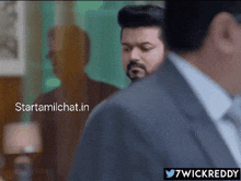 a man in a suit stands in front of a mirror with the words starttamilchat.in written above him