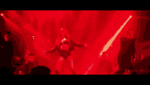 a group of people are dancing in a dark room in front of a red light .