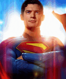 a man in a superman costume with his arms crossed looks at the camera