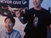 two young men are laughing in front of a never give up poster .