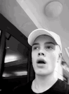 a black and white photo of a man wearing a baseball cap with the letters em on the bottom