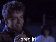 a young man is smiling while holding a drink in his hand and says greg irl .
