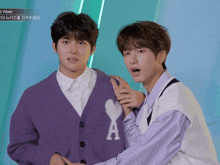 two young men are standing next to each other and one has a heart on his sweater