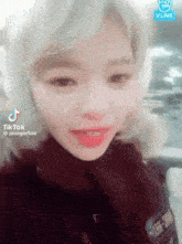 a woman is taking a selfie in front of a sign that says vlive on it