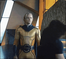 a man in a yellow superhero suit is standing next to another man in a black shirt
