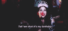 a woman wearing a pink crown is dancing in a dark room and says `` tell em that it 's my birthday ! ''