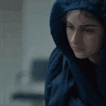 a woman wrapped in a blue blanket looks down