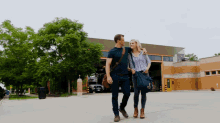 a man and a woman are walking in front of a building with a blue bag that says ' abercrombie & fitch '