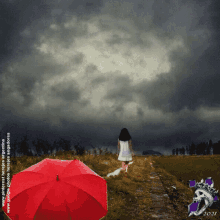 a woman walking down a path with a red umbrella in front of a cloudy sky