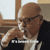 a man with glasses and a beard drinking from a glass with the words " it 's break time " written below him