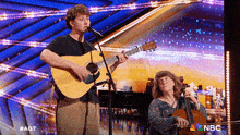 a man is singing into a microphone while a woman plays a violin