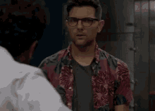 a man in a colorful shirt is talking to another man in a white shirt .