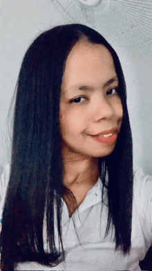 a woman with long black hair wearing a white shirt smiles for the camera