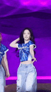 a woman in a blue shirt and jeans is dancing on a stage