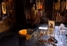 a woman is sitting on a bed in a dark room with a candle in the middle of the room .