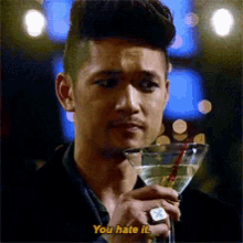 a man holding a martini glass with a straw and says you hate it