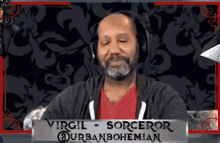 a man wearing headphones is sitting in front of a sign that says virgil sorceror