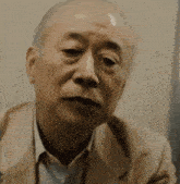 a man in a tan suit looks at the camera