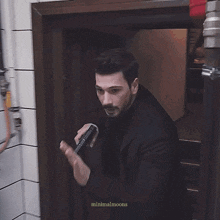 a man in a black suit is holding a microphone in front of a refrigerator with the words minimalmoons written on the bottom