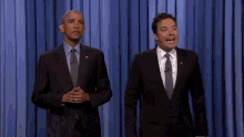 a man in a suit and tie is standing next to another man in a suit and tie on a stage .